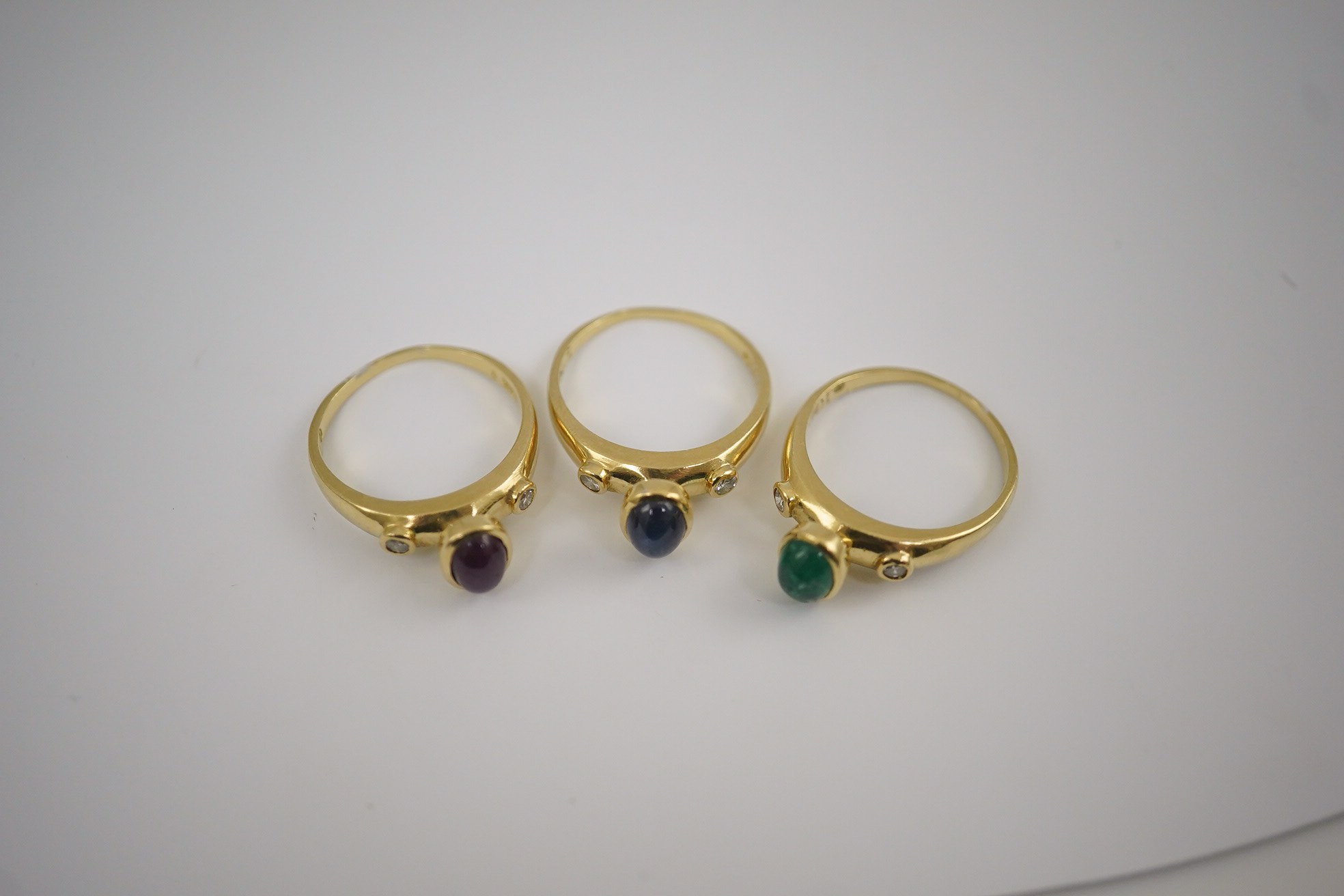 A suite of three modern 18k gold and gem set rings